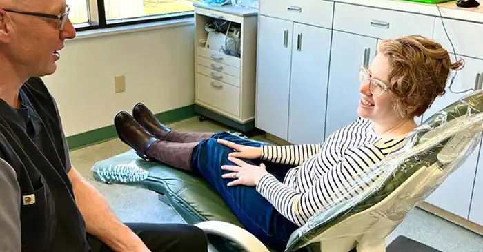 woman smiling in dental chair talking to Dr Barry Feldner